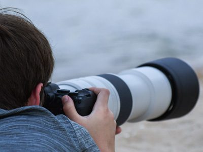A person photographing with a large telephoto lens pointed outward.