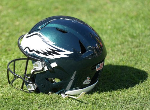 Green Philadelphia Eagles football helmet resting on grass.
