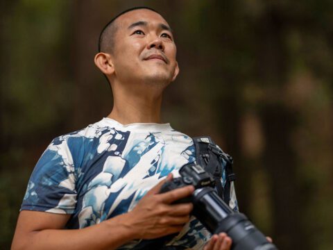 A man stands with a camera.