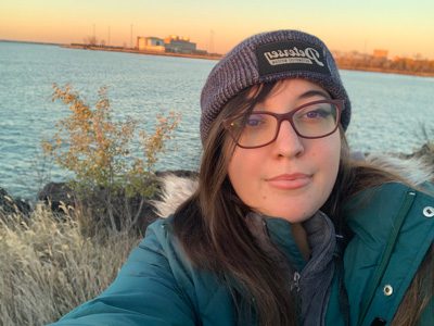 Woman wearing a hat and glasses, smiling.