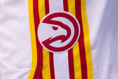 Close-up of the Atlanta Hawks logo patch on a basketball uniform, showing a stylized red hawk head over white fabric with yellow and red stripes.